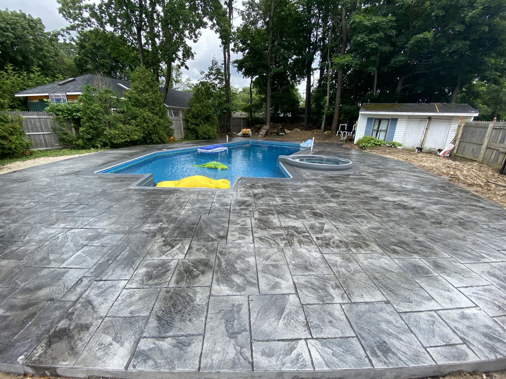 Dark stamped concrete pool patio installation by Aadvanced G.C.